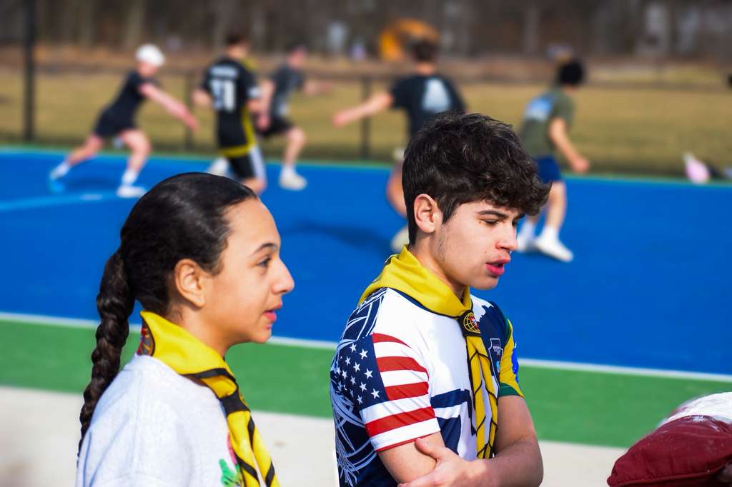 Pathfinders watching a camporee sports game on a blue court