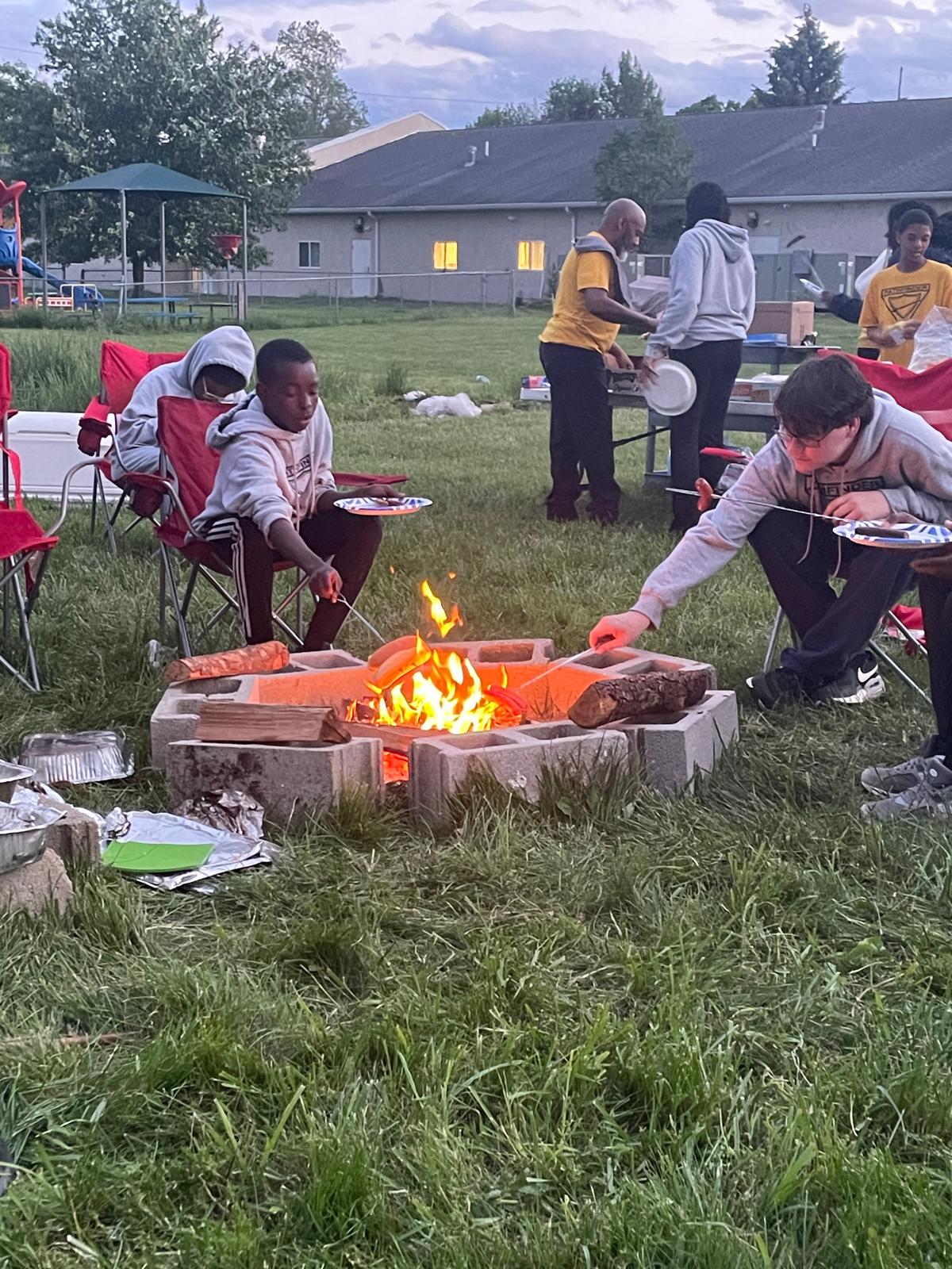 Pathfinders roasting food around a bonfire